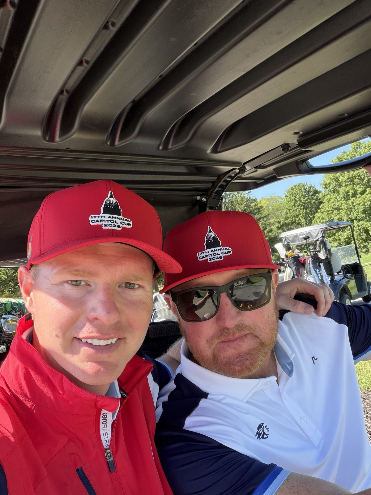 Two players in a cart wearing Capitol Cup hats